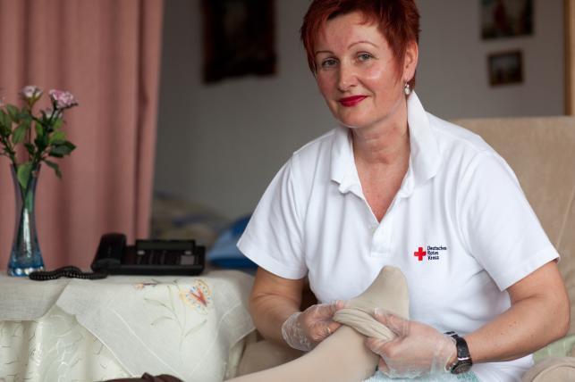 Ambulante Pflege 01 Deutsches Rotes Kreuz DRK, Einsatzbereiche / Aktivitaeten / Leistungen / Aufgaben, Sozialarbeit, Ambulante Pflege Hauspflege haeusliche Pflege, Strumpf, anziehen, Einmalhandschuhe, Betreuung