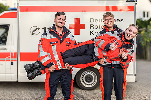 Rettungsdienstkollegen heben Kollegin in die Höhe