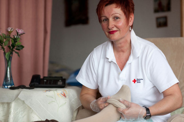 Ambulante Pflege 01 Deutsches Rotes Kreuz DRK, Einsatzbereiche / Aktivitaeten / Leistungen / Aufgaben, Sozialarbeit, Ambulante Pflege Hauspflege haeusliche Pflege, Strumpf, anziehen, Einmalhandschuhe, Betreuung