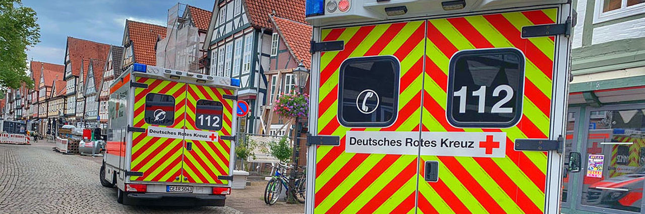 Zwei Rettungswagen stehen in der Celler Altstadt vor historischen Fachwerkhäusern. Die Fahrzeuge sind von hinten zu sehen, eingebettet in das Stadtbild.