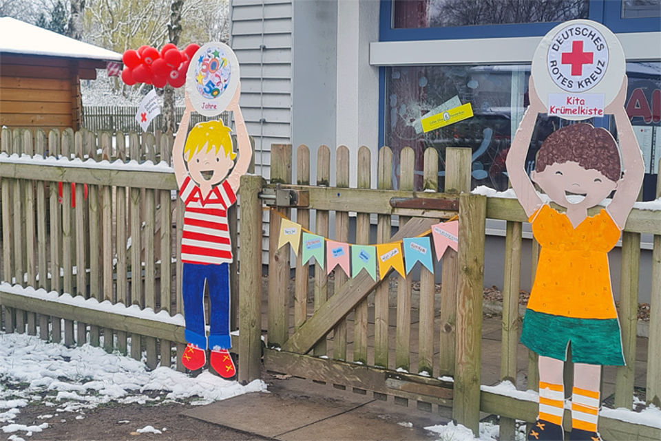 Kinderfiguren vorm Gartenzaun