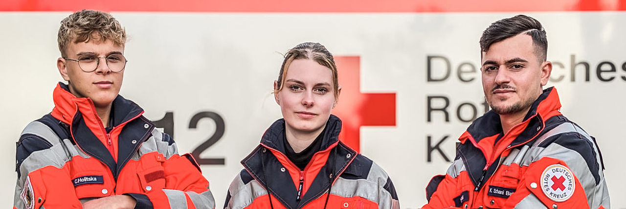 Drei Rettungsdienstkollegen vor einem Rettungswagen