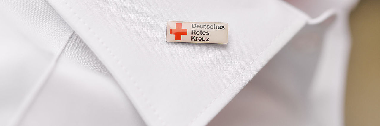 Symbolfoto Weißer Hemdkragen mit DRK-Pin