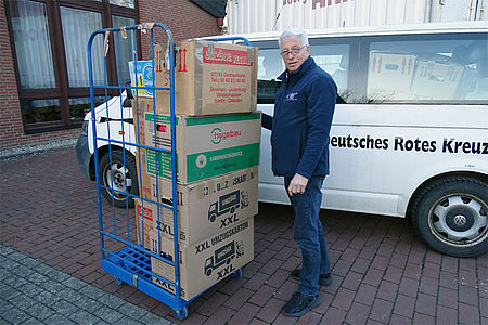 Mann bringt Pakete mit Kleidungsstücken zum Sammelort