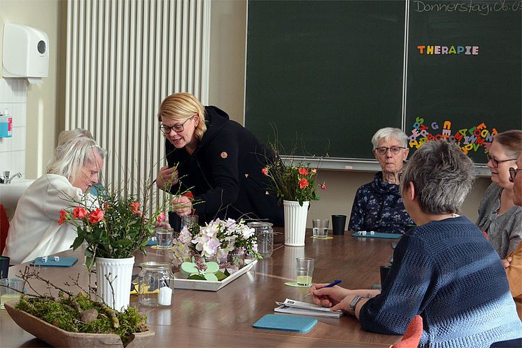 Gruppenbetreuung in der Tagespflege, Pflegekraft erklärt Tagespflegegast ein Spiel