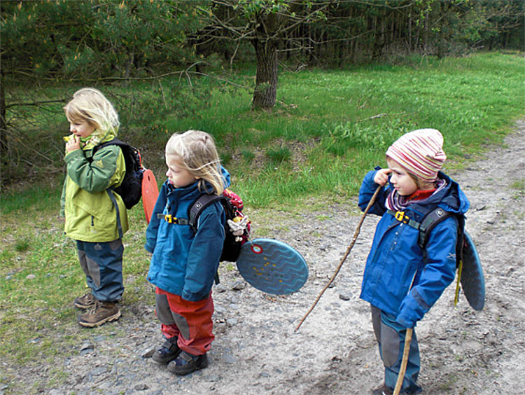 Drei Kinder spazieren auf einem Waldweg
