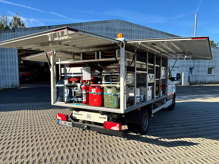 Gerätewagen Sanität mit vollständig geöffneten Klappen, seitlich von hinten aufgenommen, zeigt die einsatzbereite Ausstattung.