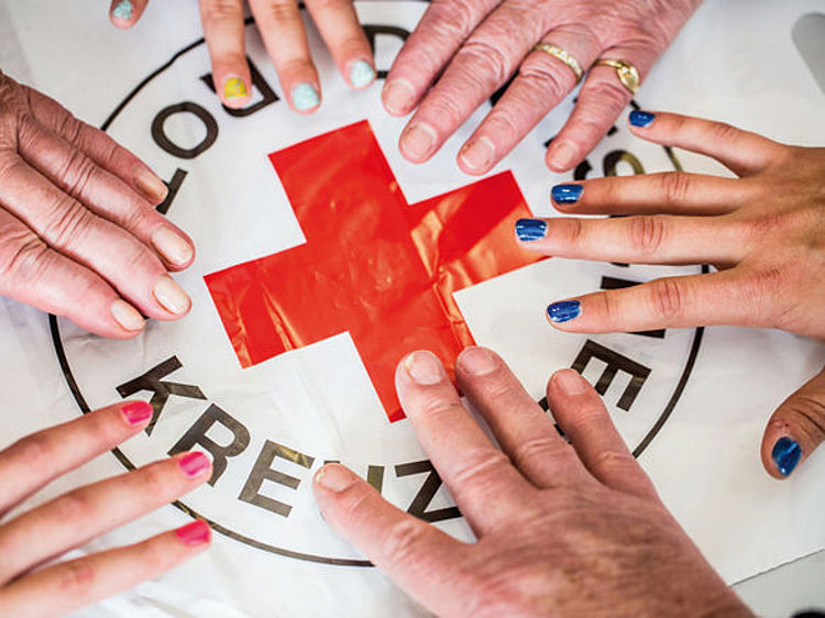 Mitglied werden - Hände liegen auf einem Rotkreuz-Untergrund