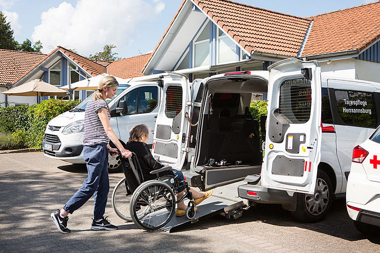 Mobilität mit Unterstützung – Pflegerin begleitet eine Seniorin im Rollstuhl zum Transport.