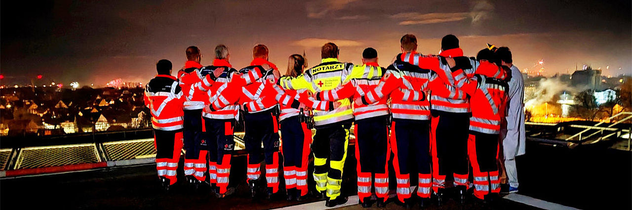 In der Silvesternacht stehen Rettungsdienstmitarbeiter und ein Notarzt Arm in Arm auf dem Dach des Allgemeinen Krankenhauses (AKH) und betrachten gemeinsam das farbenprächtige Feuerwerk.