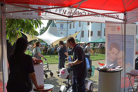 Rotkreuzmitarbeiter beraten Kunden am Stand.