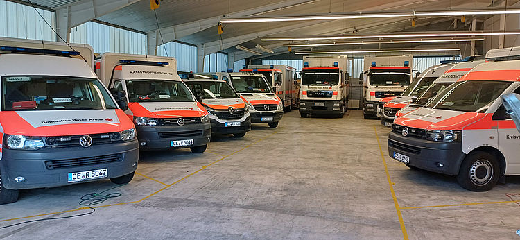 Innenansicht einer Fahrzeughalle des Katastrophenschutzes mit mehreren Einsatzfahrzeugen.