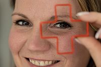 Frau lächelnd, hält Rotkreuz-Ausstechform vorm Auge