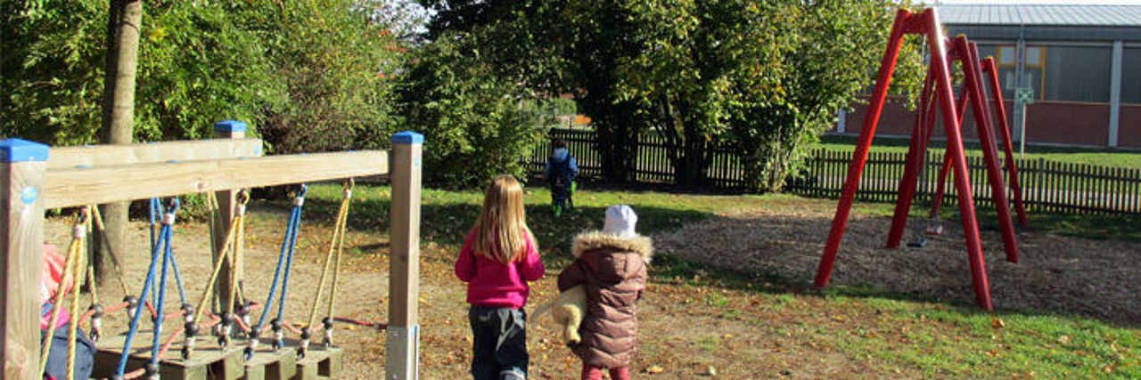 Kinder auf dem Außengelände vor Spielgeräten